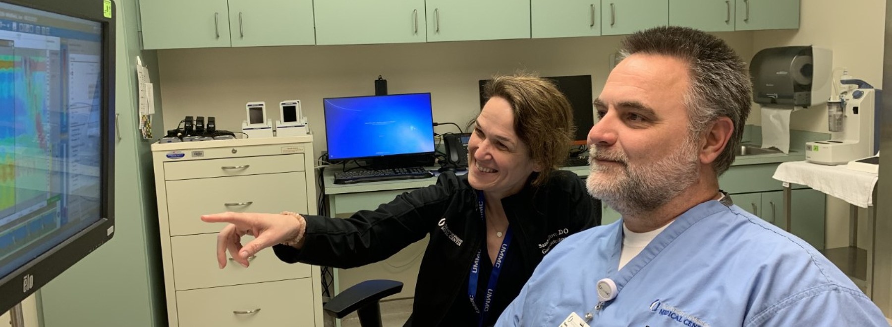 Two physicians confer gathered around a computer.